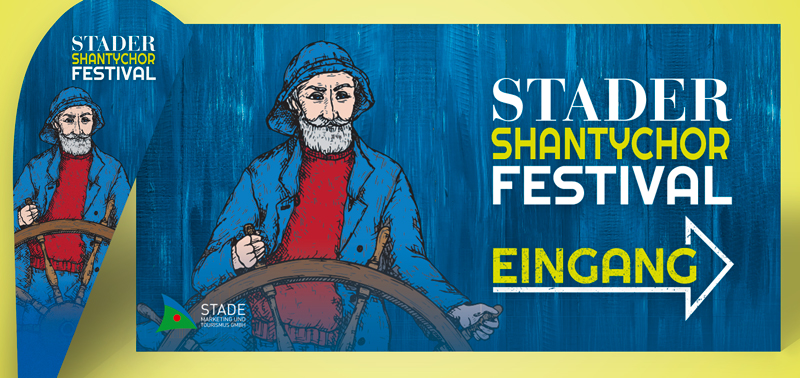 Eine bedruckte Bow-Flag (Flagge) und ein Bauzaunbanner mit einem Seemann vor einem Holz-Hintergrund, der das Steuerrad eines Schiffs in den Händen hält. Aufschrift ist "Stader Shantychor Festival".