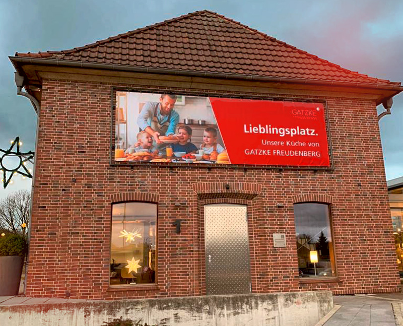 Das E-Werk in Stade mit einem Banner. Darauf ist links eine glückliche Familie in der Küche und rechts die Aufschrift „Lieblingsplatz. Unsere Küche von Gatzke Freudenberg“ und das Getzke Freudenberg-Logo zu sehen.
